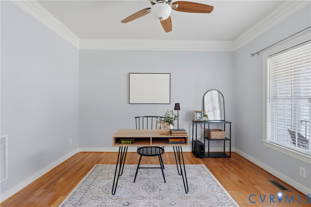 Room featuring wood-finish flooring, crown molding, a ceiling fan, and window blinds