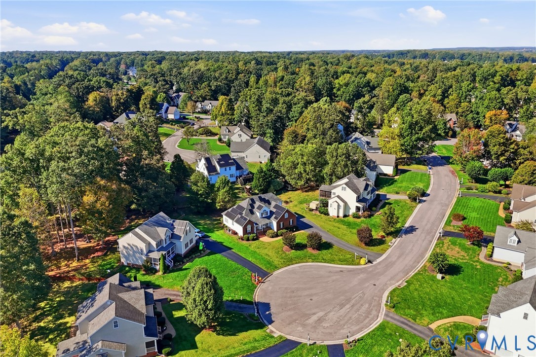 Aerial perspective of a residential neighborhood featuring cul-de-sac streets, expansive green spaces, mature tree canopies, and traditional detached homes