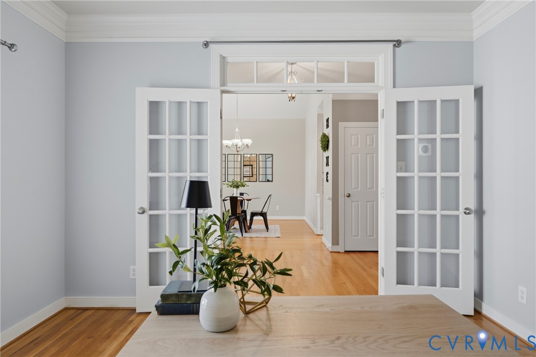 Double French doors with a multi-pane transom window, wood-finish flooring, and crown molding
