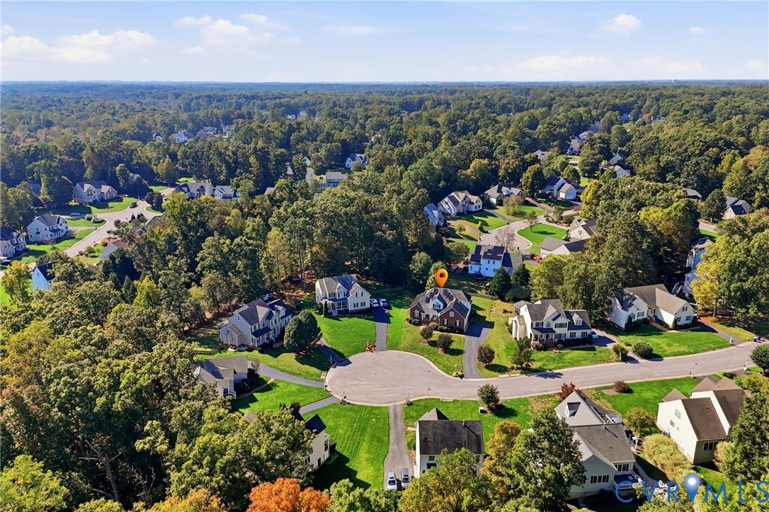 Aerial perspective of a multi-story residence situated on a cul-de-sac lot, featuring an attached multi-car garage, steep-pitched roofline, and established mature tree canopy