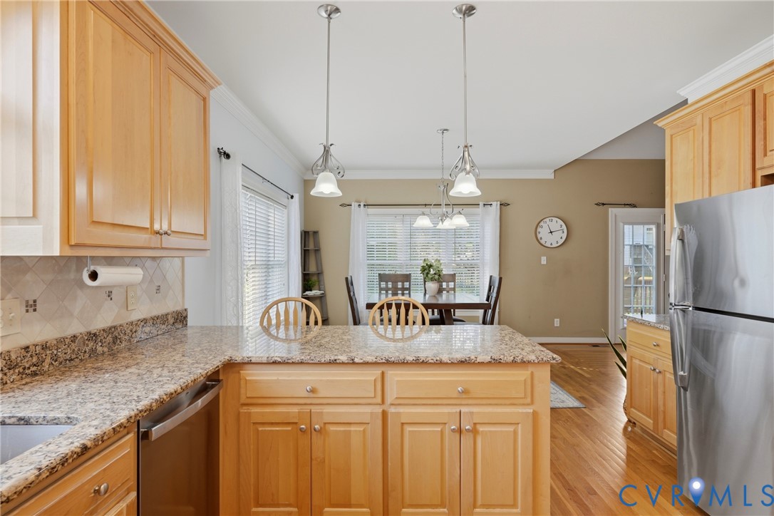 Kitchen featuring shaker-style cabinetry, stone countertops, stainless steel refrigerator, hanging pendant lighting, and wood-finish flooring