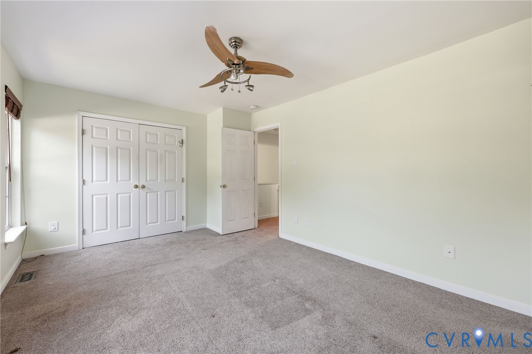 Interior room featuring wall-to-wall carpeting, a multi-paneled double closet, and a ceiling fan with integrated light fixture