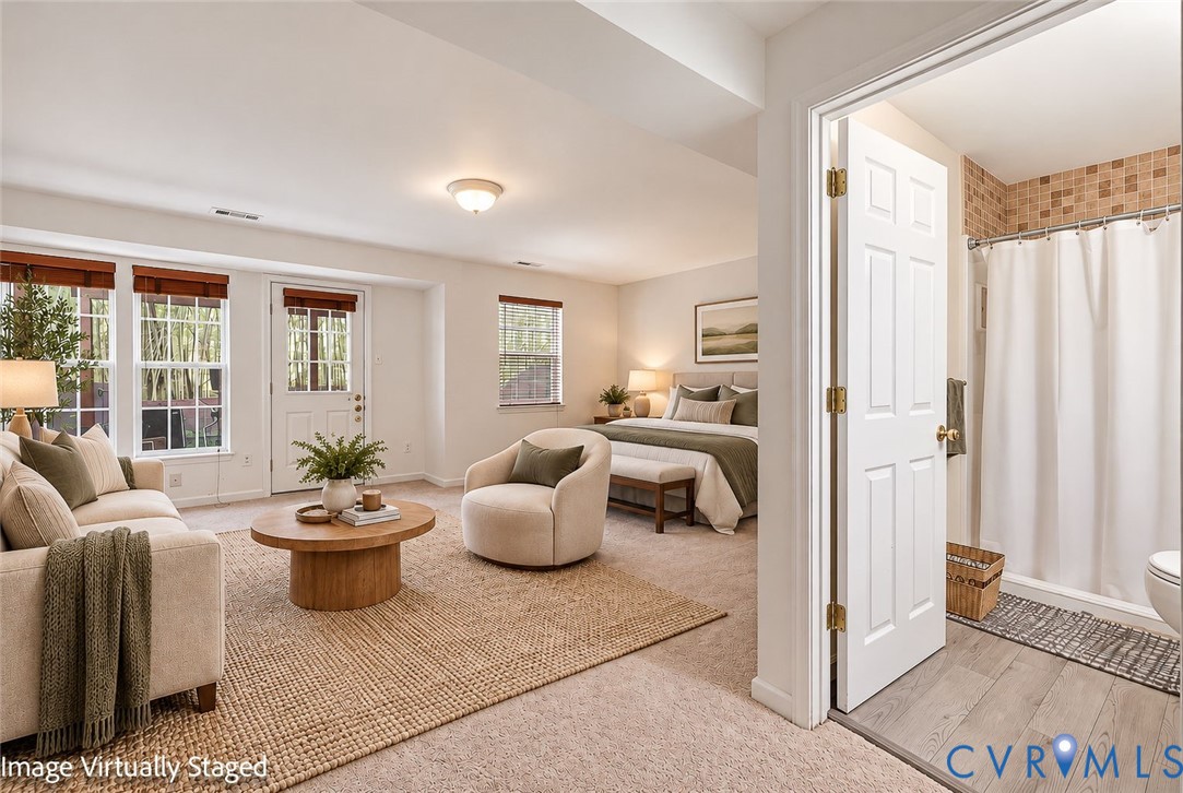 Neutral-toned carpeted flooring, multiple oversized windows, exterior-access door, and a tiled shower enclosure with wood-finish flooring