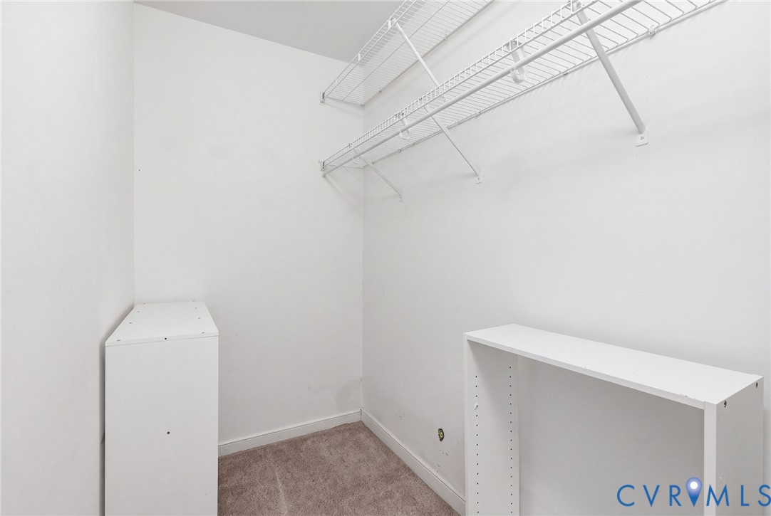 Storage area featuring white wire shelving units, carpeted flooring, and white built-in cabinetry