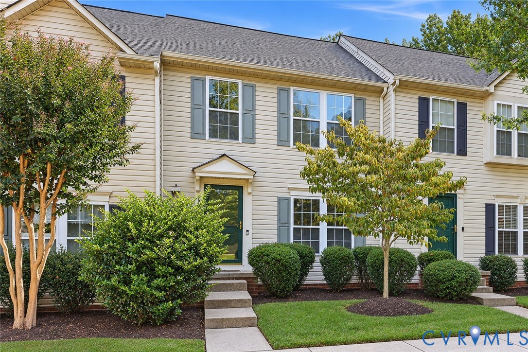 Two-story exterior featuring light-colored horizontal siding, dark shutters, multi-pane windows, and concrete walkways Two-story exterior featuring light-colored horizontal siding, dark shutters, multi-pane windows, and concrete walkways