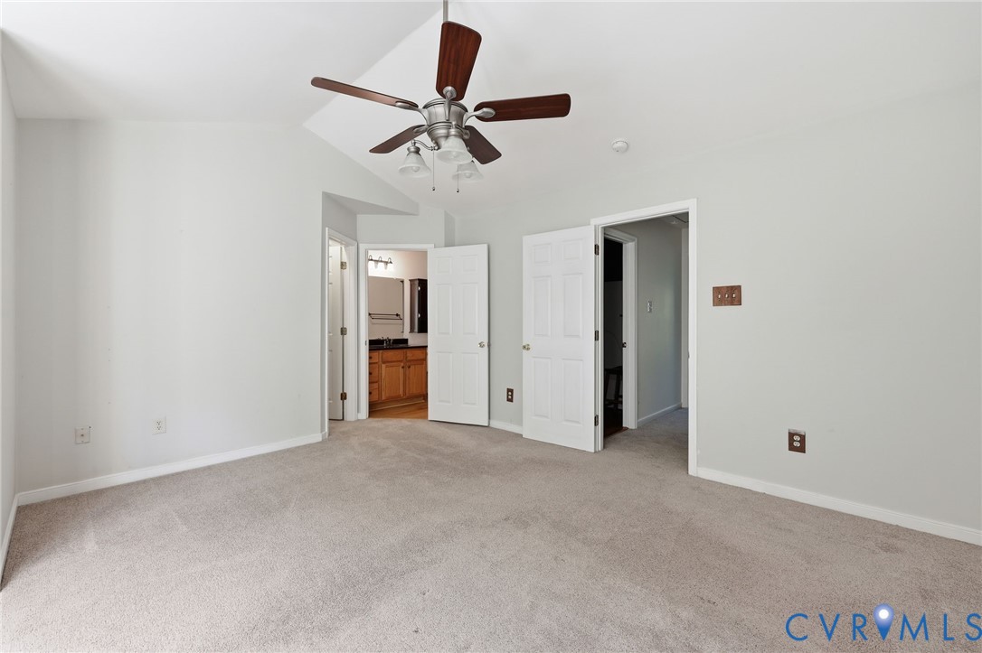 Vaulted ceiling with a five-blade ceiling fan, wall-to-wall carpeting, and six-panel interior doors