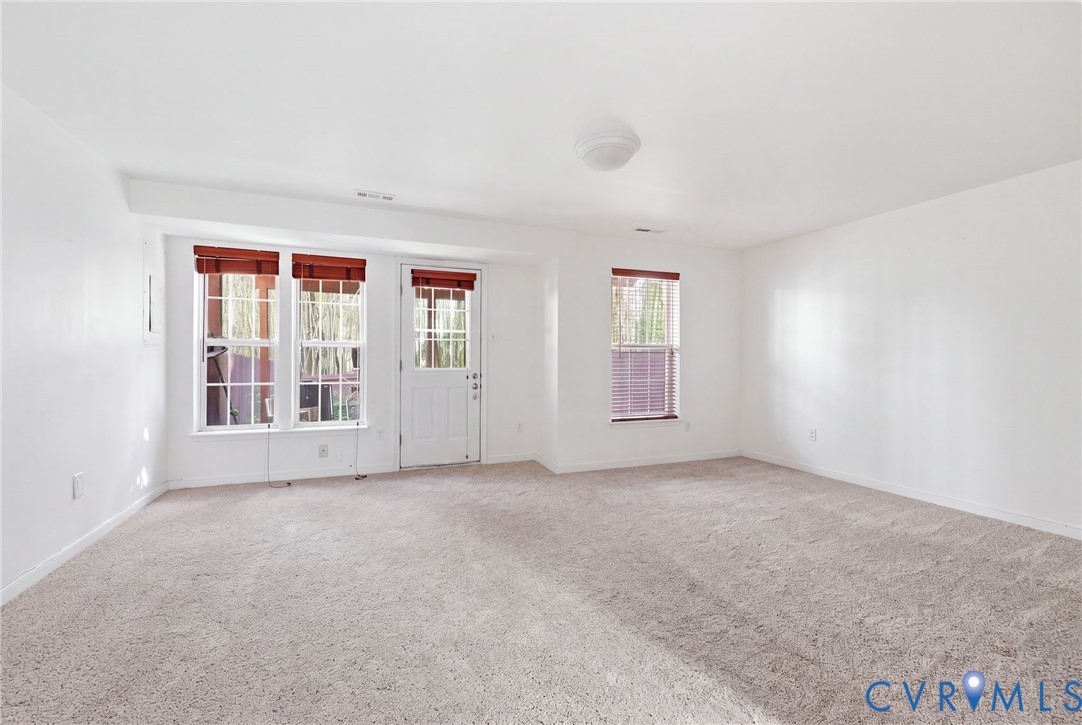 Neutral-toned carpeting, high-gloss white walls, and triple multi-lite windows with exterior glass door access