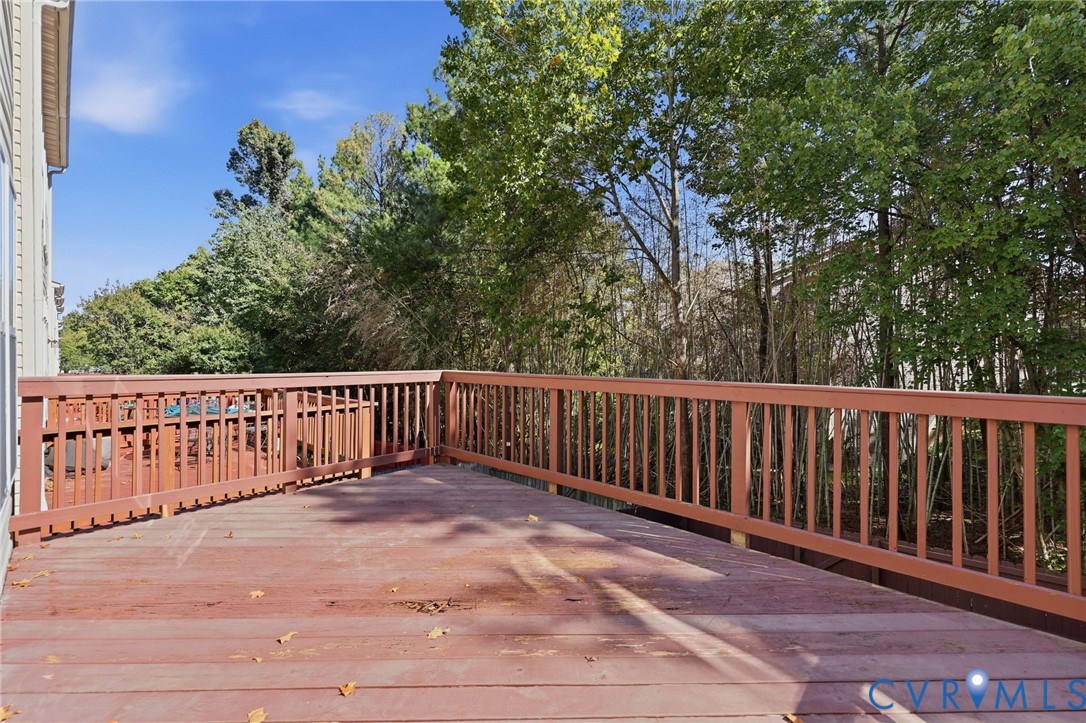 Elevated wood deck featuring vertical slat railings and mature tree canopy backdrop