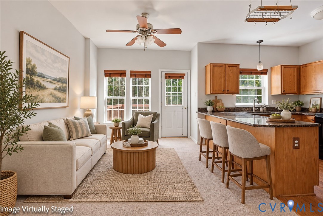 Kitchen featuring a peninsula with countertop seating, wood cabinetry, stone-finish countertops, natural lighting from multi-pane windows, and a ceiling fan Kitchen featuring a peninsula with countertop seating, wood cabinetry, stone-finish countertops, natural lighting from multi-pane windows, and a ceiling fan