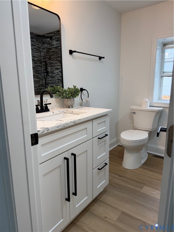 White cabinetry with black hardware, stone-composite countertop, rectangular undermount sink, matte black faucet fixtures, and wood-finish flooring White cabinetry with black hardware, stone-composite countertop, rectangular undermount sink, matte black faucet fixtures, and wood-finish flooring