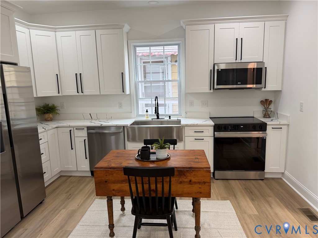 Kitchen featuring white white cabinetry, quartz countertops, vinyl flooring, and stainless steel appliance package and sink. Kitchen featuring white white cabinetry, quartz countertops, vinyl flooring, and stainless steel appliance package and sink.
