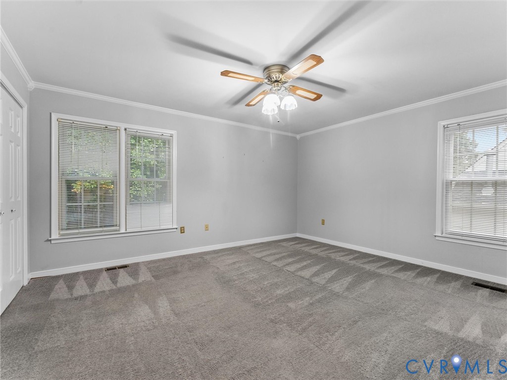 Neutral wall finishes, plush carpeting, ceiling fan with integrated lighting, and multiple windows with blinds
