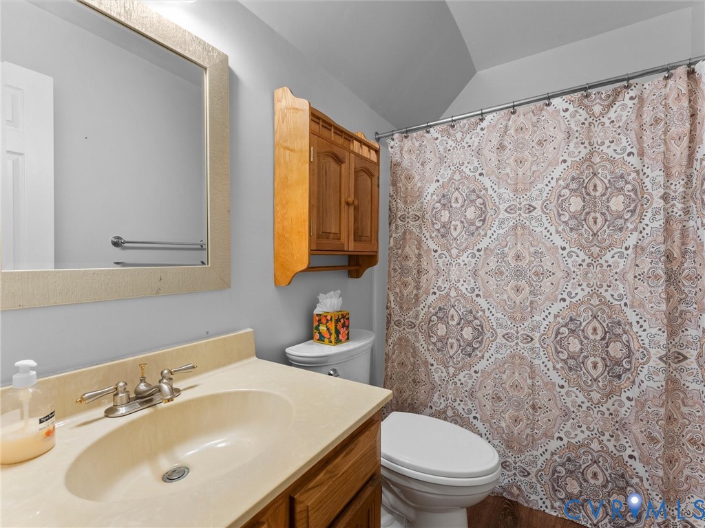 Bathroom featuring a vanity with integrated basin, wall-mounted wooden cabinetry, a rectangular mirror, and a combination bathtub and shower enclosure
