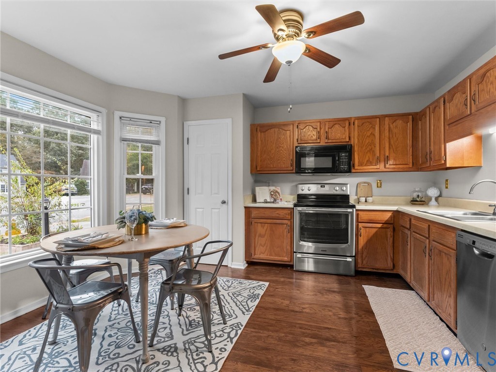 Kitchen featuring oak-finish cabinetry, stainless steel appliances, wood-finish flooring, and a bay window Kitchen featuring oak-finish cabinetry, stainless steel appliances, wood-finish flooring, and a bay window