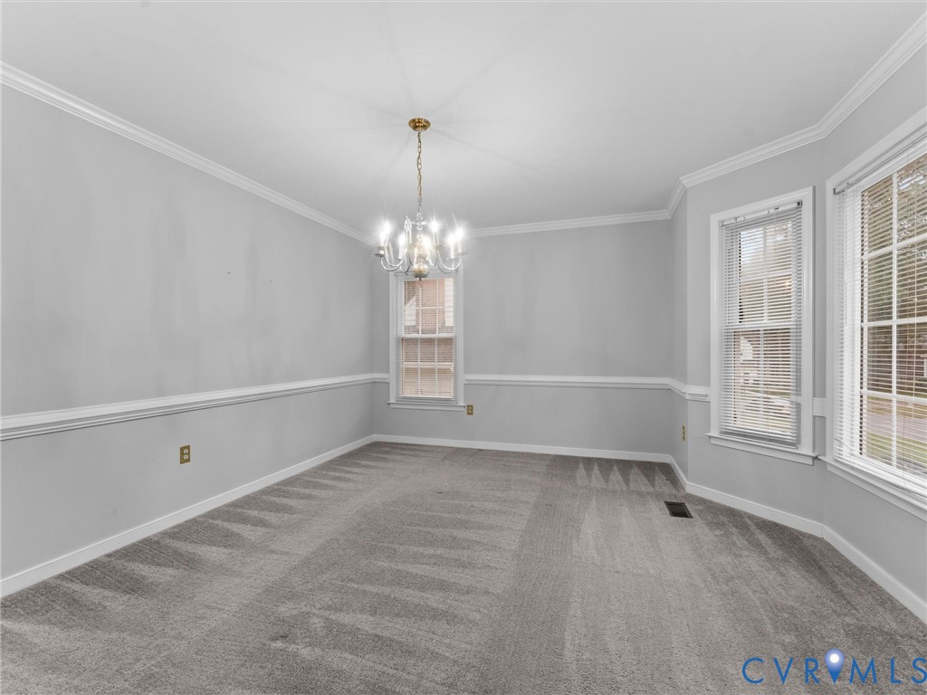 Room featuring crown molding, chair rail trim, multi-pane windows, and a multi-arm chandelier