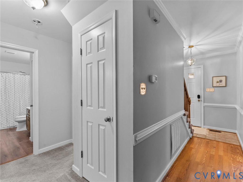 Interior hallway featuring wood-finish flooring, chair rail molding, six-panel interior doors, and a multi-light pendant fixture