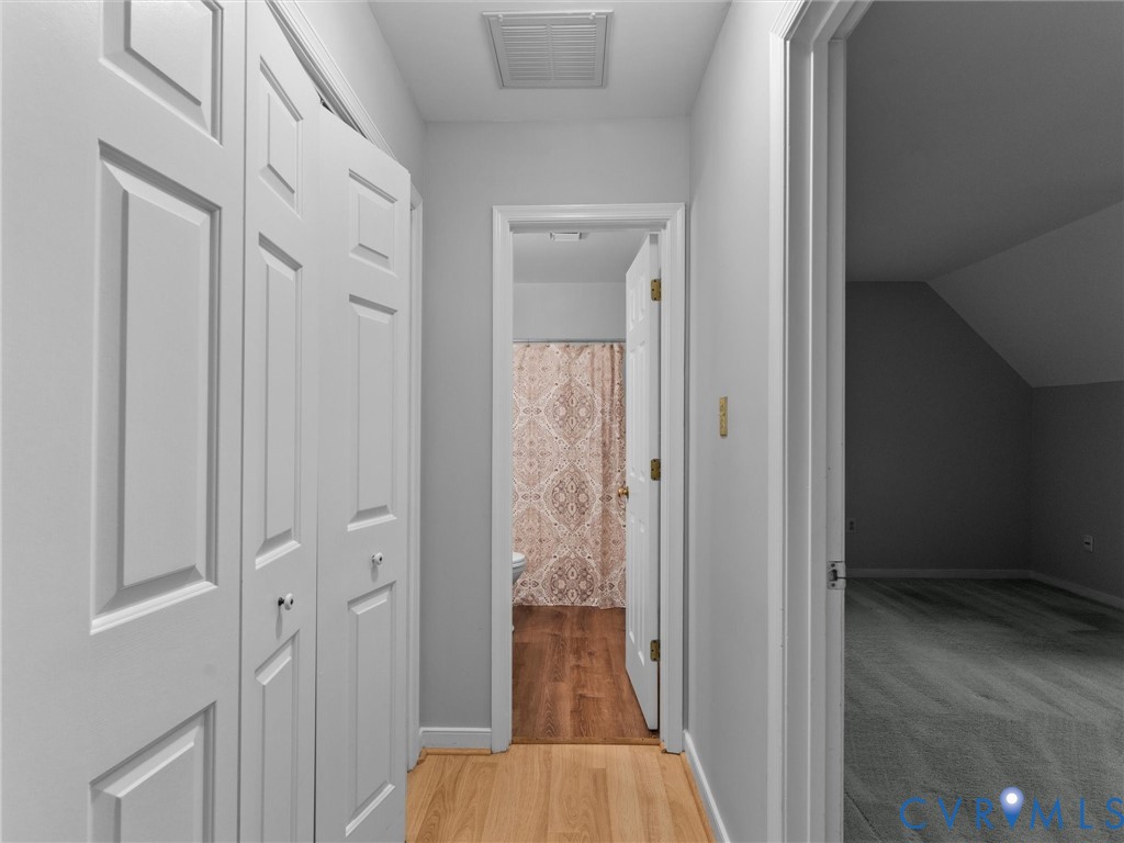 Hallway featuring paneled bi-fold closet doors, light-toned wood-finish flooring, and neutral wall paint