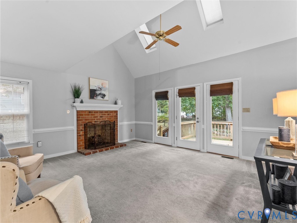 Vaulted ceilings featuring dual skylights, a brick-surround fireplace with a mantel, and three glass-paneled doors Vaulted ceilings featuring dual skylights, a brick-surround fireplace with a mantel, and three glass-paneled doors
