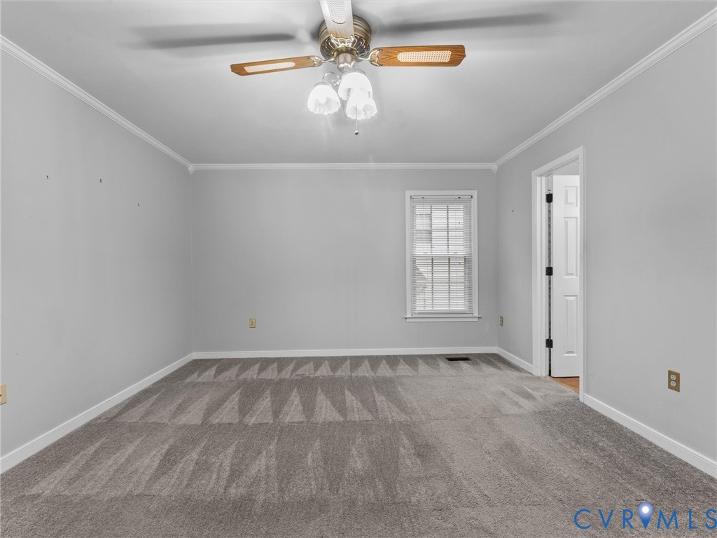 Room featuring neutral wall tones, wall-to-wall carpeting, crown molding, a multi-pane window, and a ceiling fan with integrated lighting