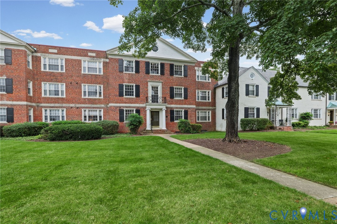 Traditional brick exterior featuring a multi-story facade, gabled rooflines, decorative pediments, shuttered windows, and a covered entryway