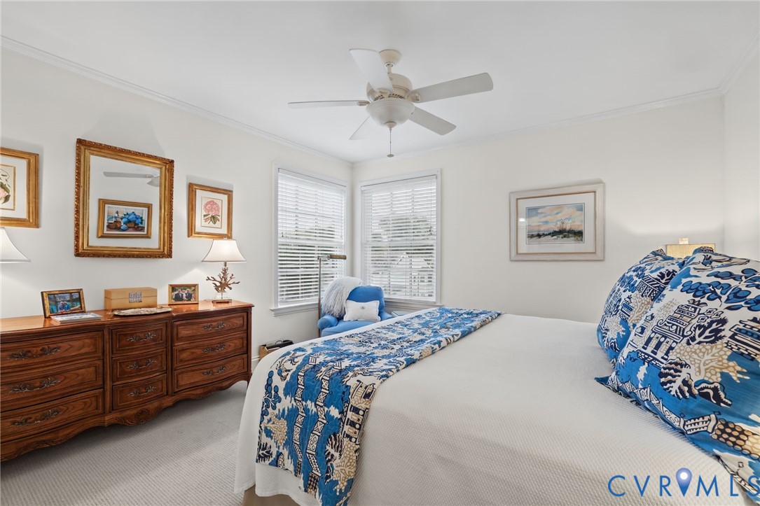 Interior space featuring neutral wall tones, wall-to-wall carpeting, dual windows with horizontal blinds, and a multi-blade ceiling fan