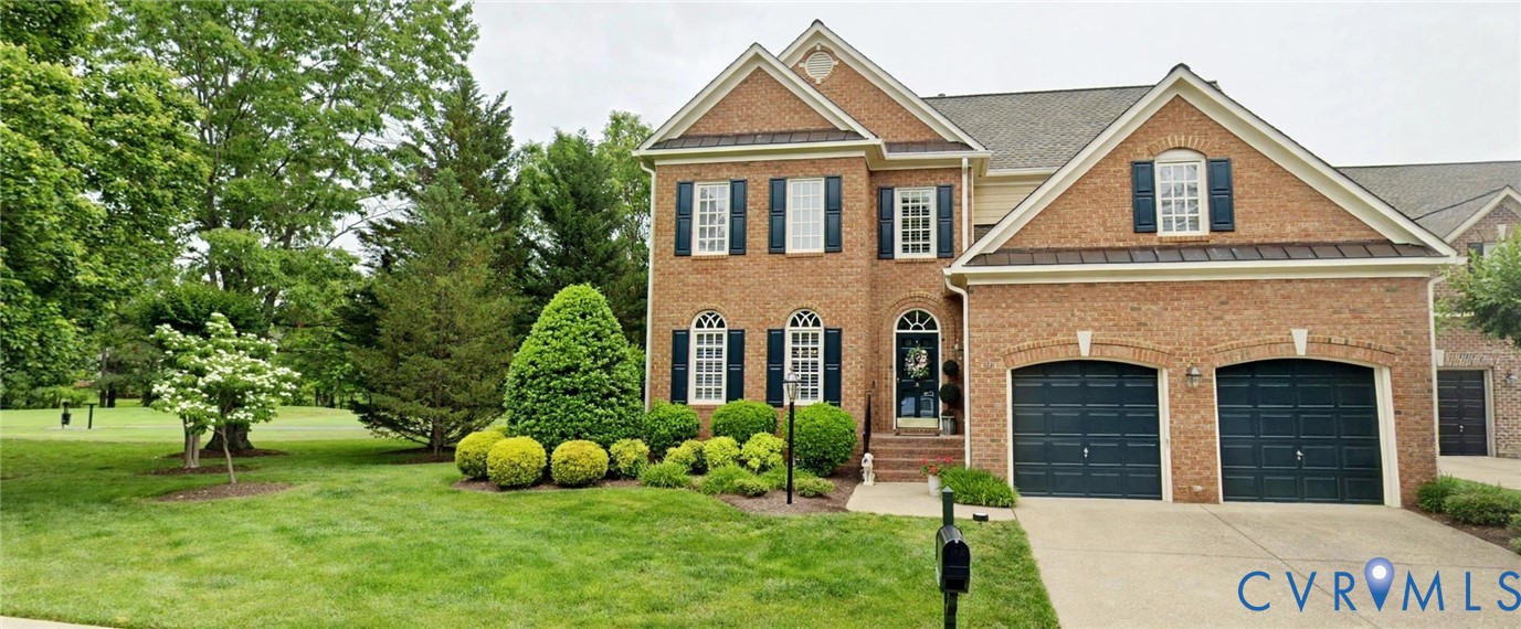 Brick facade residence featuring two attached garages, a concrete driveway, and a landscaped front yard with mature trees