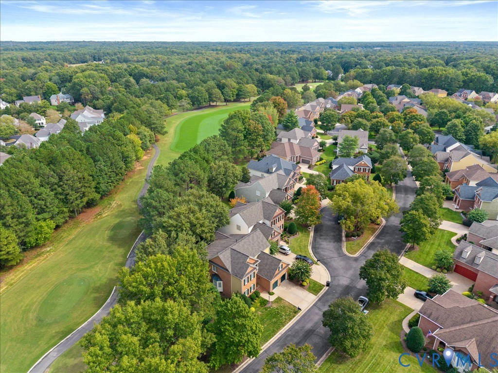 Residential community with mature tree canopies, multi-story homes, and a manicured golf course bordering the property
