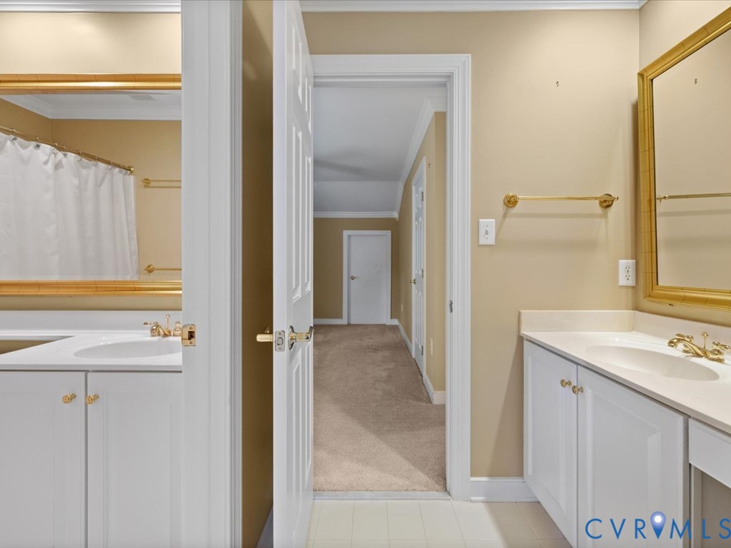 Dual vanities with integrated sinks, white cabinetry, and gold-toned hardware