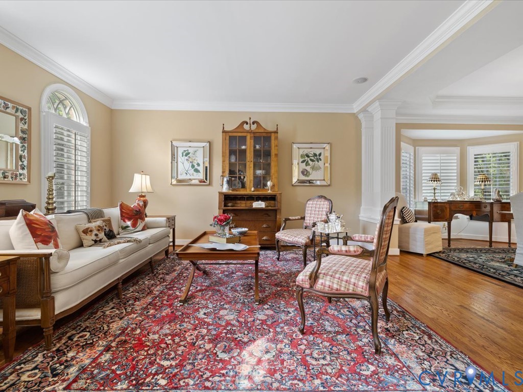 Hardwood flooring, arched window, crown molding, built-in display cabinet, and plantation shutters