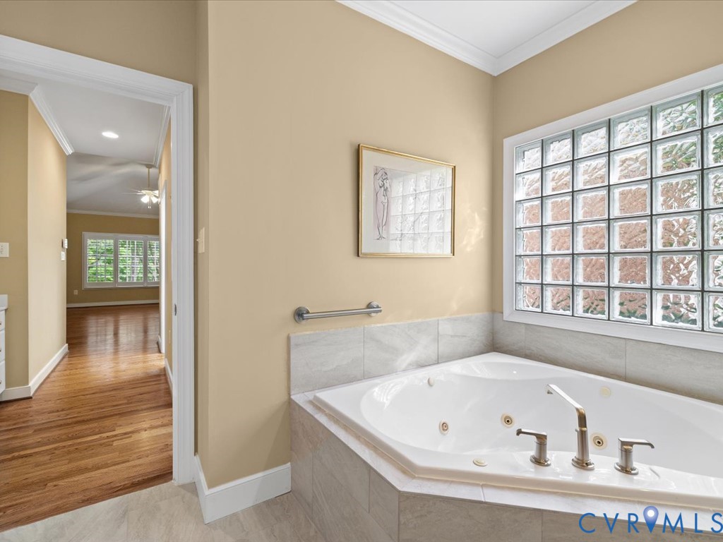 Jetted soaking tub with a tiled surround, glass block window, and brushed nickel fixtures