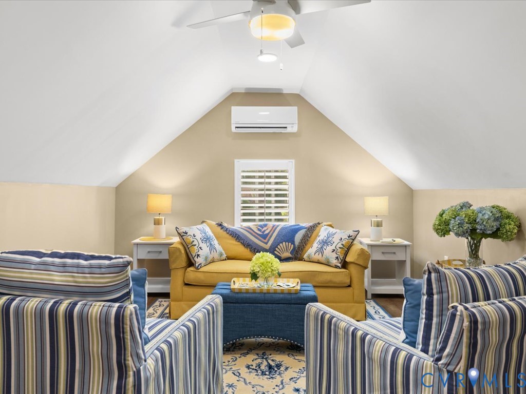 Vaulted ceiling featuring a ceiling fan, window with plantation shutters, and a wall-mounted climate control unit