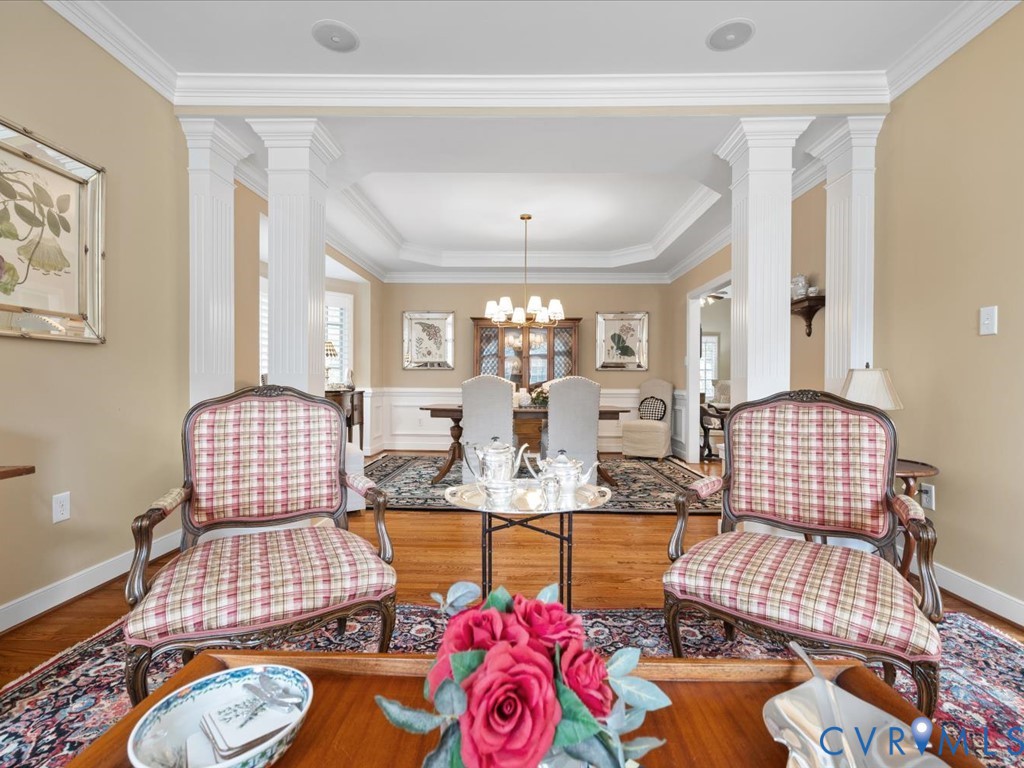 Hardwood flooring, decorative columns, extensive crown molding, chair rail molding, and a tray ceiling