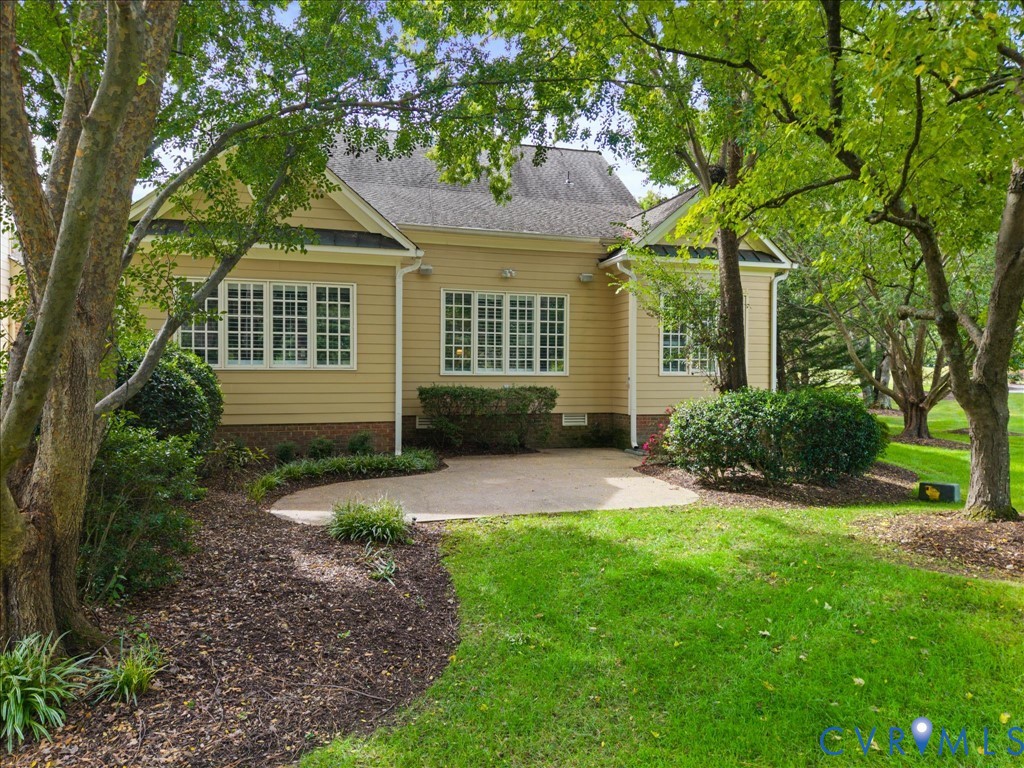 Rear exterior with beige siding, multiple pane windows, and a concrete patio