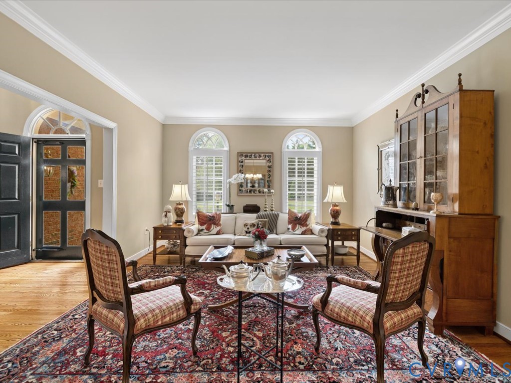 Hardwood flooring, arched transom window, crown molding, and plantation shutters