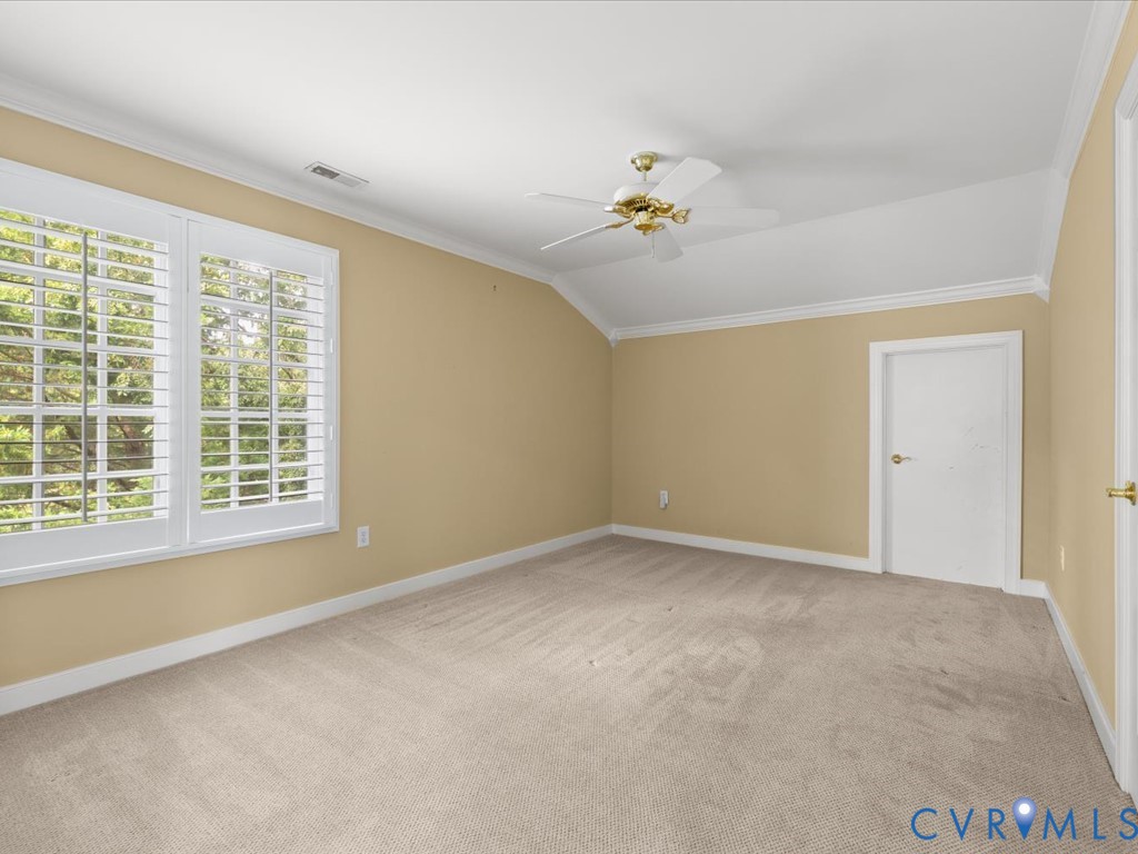 Vaulted ceiling with a ceiling fan, carpeted flooring, and white plantation shutters on windows