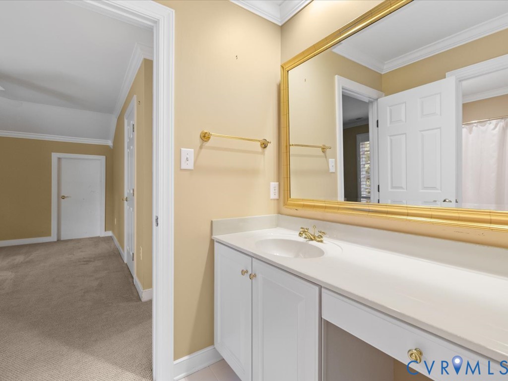 Vanity with an integrated sink, white cabinetry, gold-finish hardware, and an expansive wall-mounted mirror
