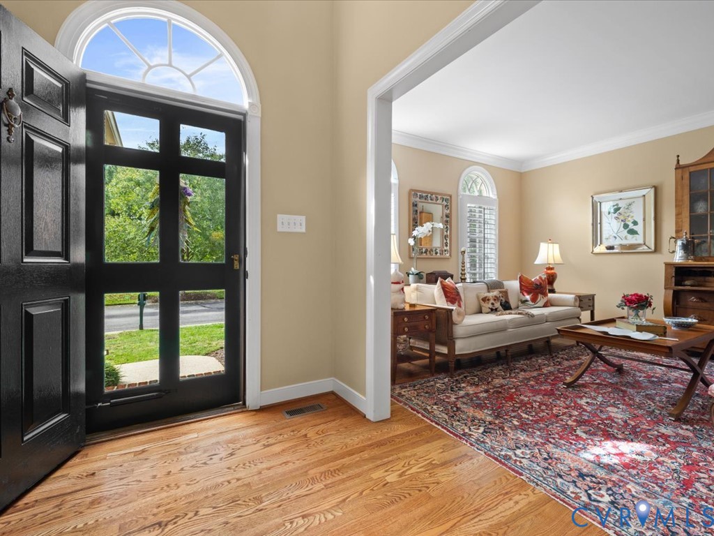 Hardwood flooring, arched transom window, paneled entry door, interior wall trim, and cased opening