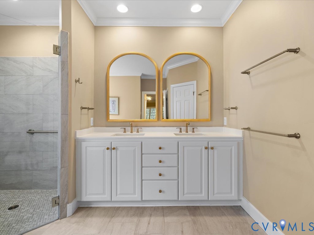 Dual sink vanity with white cabinetry and gold-toned hardware