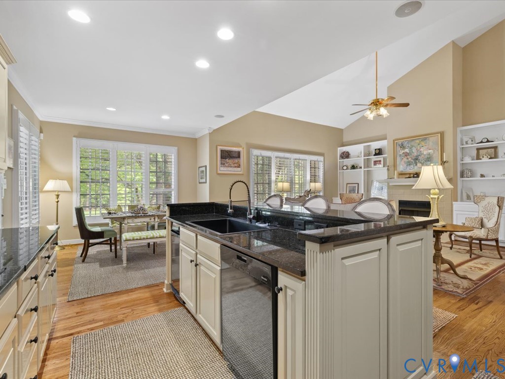 Kitchen island with dark countertops, built-in dishwasher, and a deep sink with a gooseneck faucet