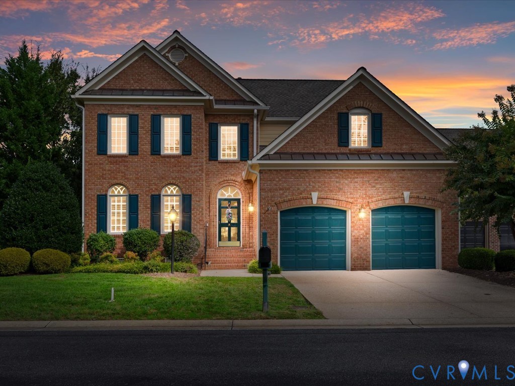 Brick exterior with dark shutters, dual garage doors, and a paved driveway Brick exterior with dark shutters, dual garage doors, and a paved driveway