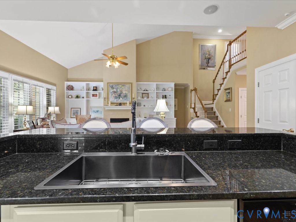 Kitchen featuring a stainless steel undermount sink, dark speckled countertops, and white cabinetry