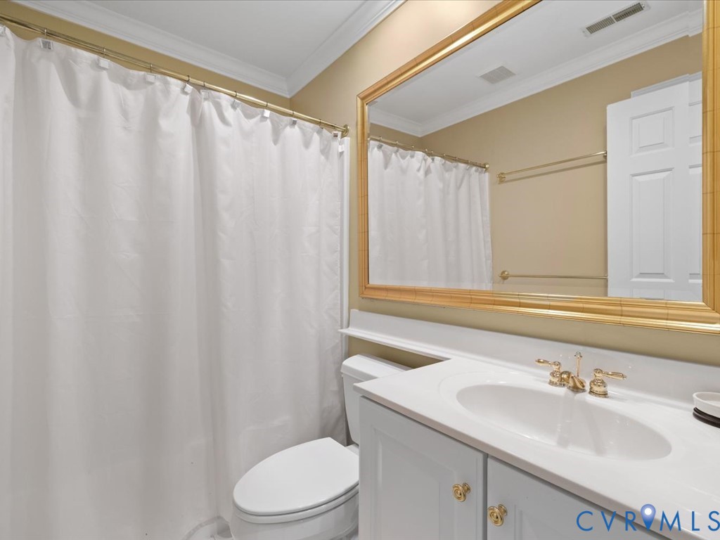 Bathroom featuring a single vanity, undermount sink, gold-tone hardware, and a framed mirror