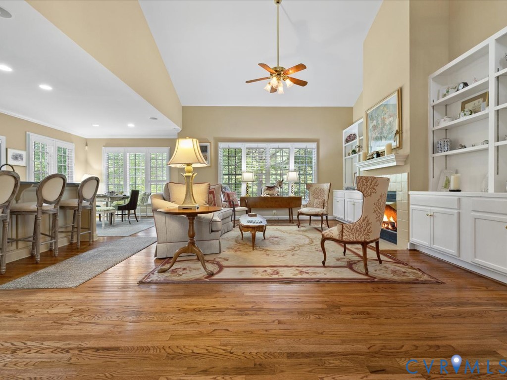 Hardwood flooring throughout, vaulted ceiling, built-in shelving, fireplace, and extensive windows