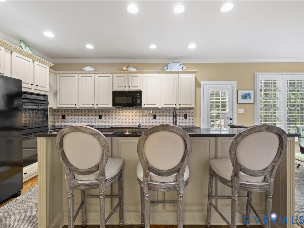 Kitchen featuring recessed lighting, paneled cabinetry, dark countertops, tiled backsplash, and built-in appliances