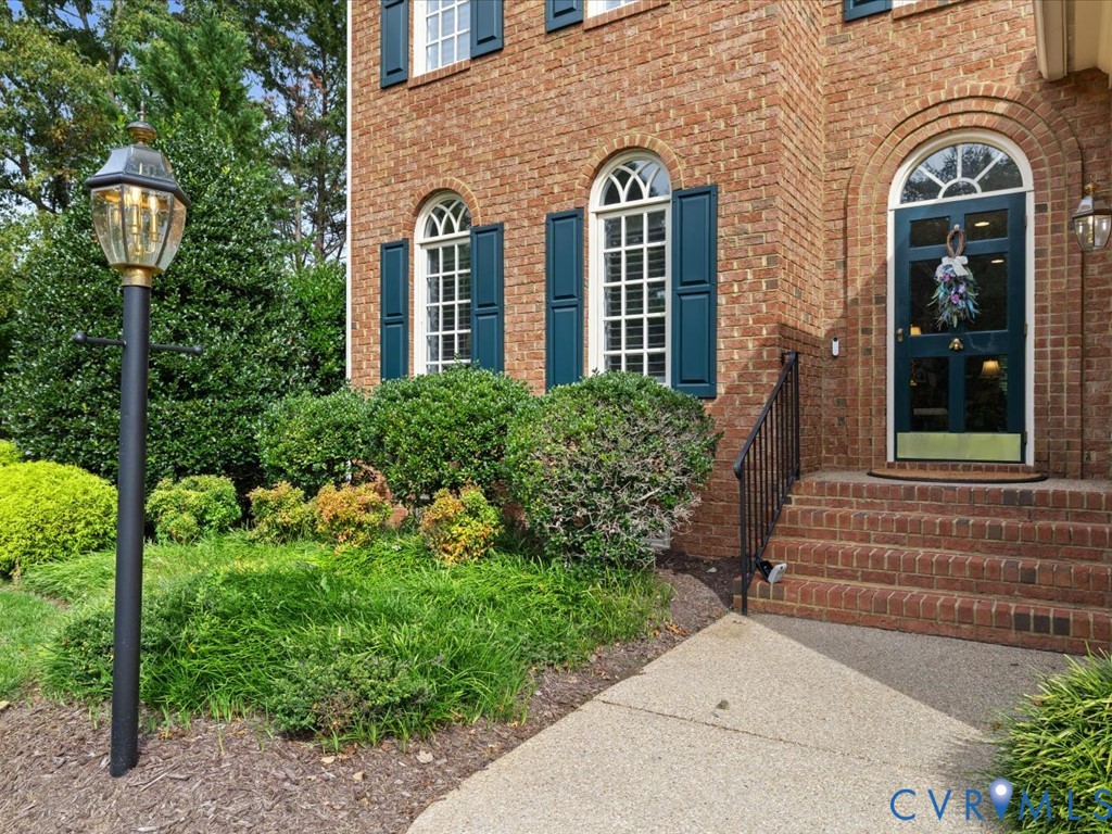 Brick exterior with arched windows, decorative shutters, a prominent entry door, and a traditional lantern-style post light