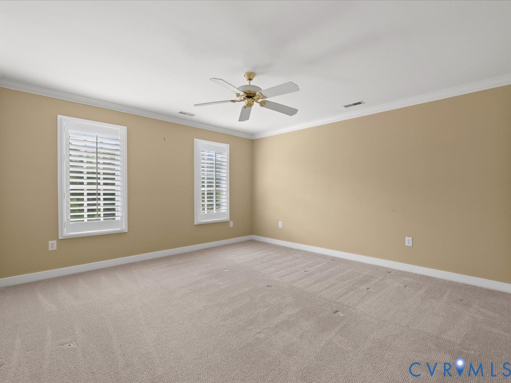 Recessed lighting, ceiling fan, crown molding, two windows with plantation shutters, and carpeted flooring