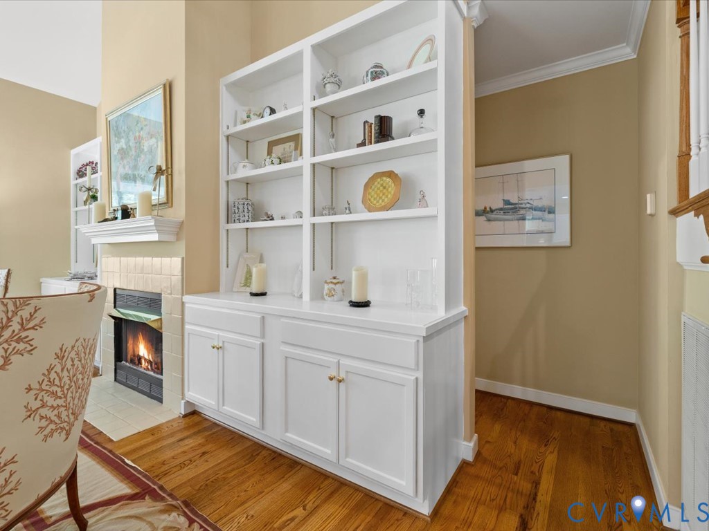 Built-in shelving unit with lower cabinetry, wood-finish flooring, and crown molding