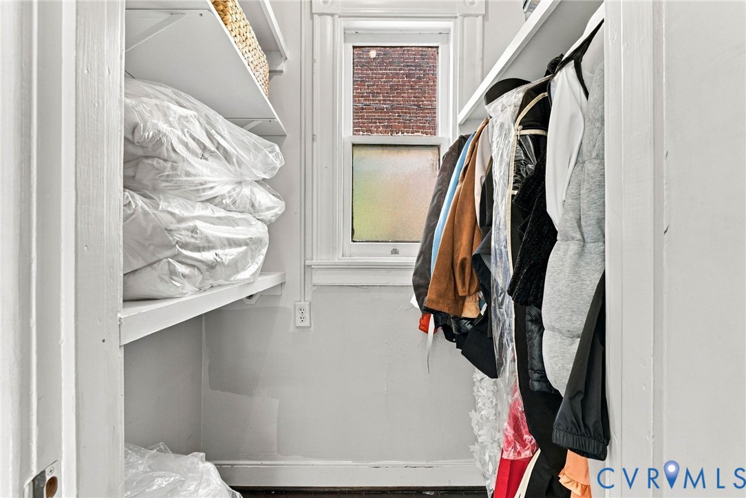 Storage space featuring white built-in shelving and a central window with white millwork trim