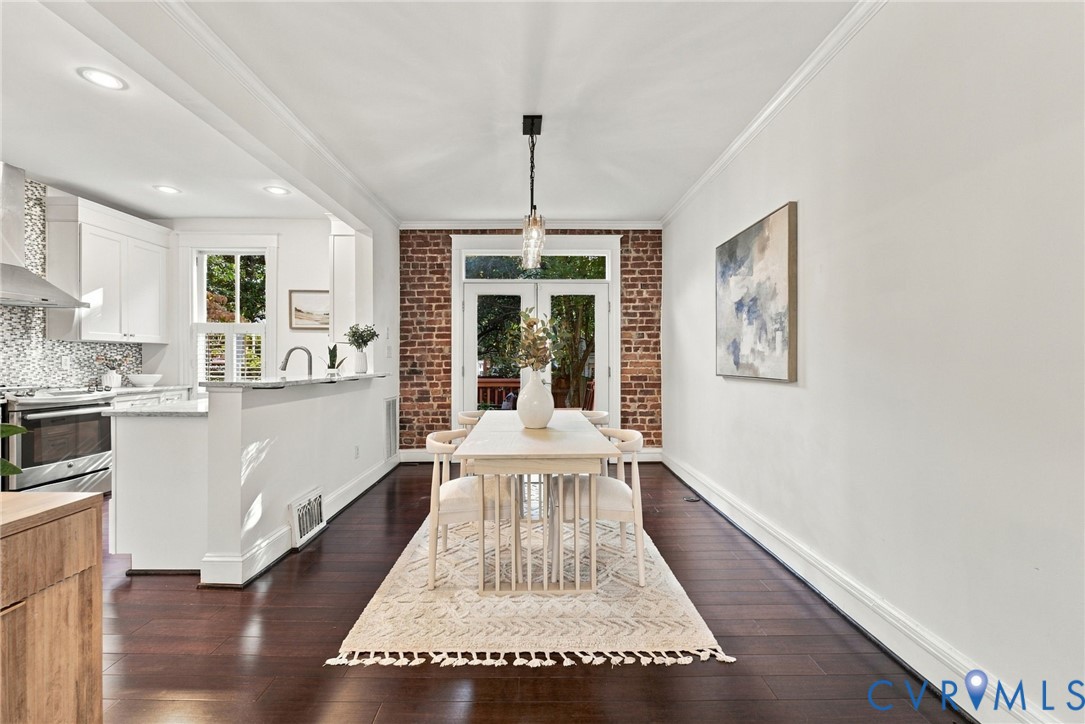 Open-concept interior featuring exposed brick walls, dark wood-finish flooring, recessed lighting, and glass-paned French doors