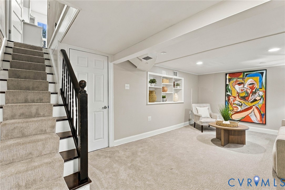 Carpeted staircase with dark-finished wood balusters and handrail, recessed ceiling lighting, and built-in wall shelving